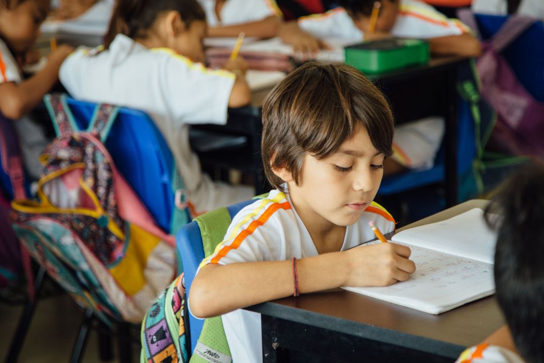 male student at K'iin Beh writes in notebook during class